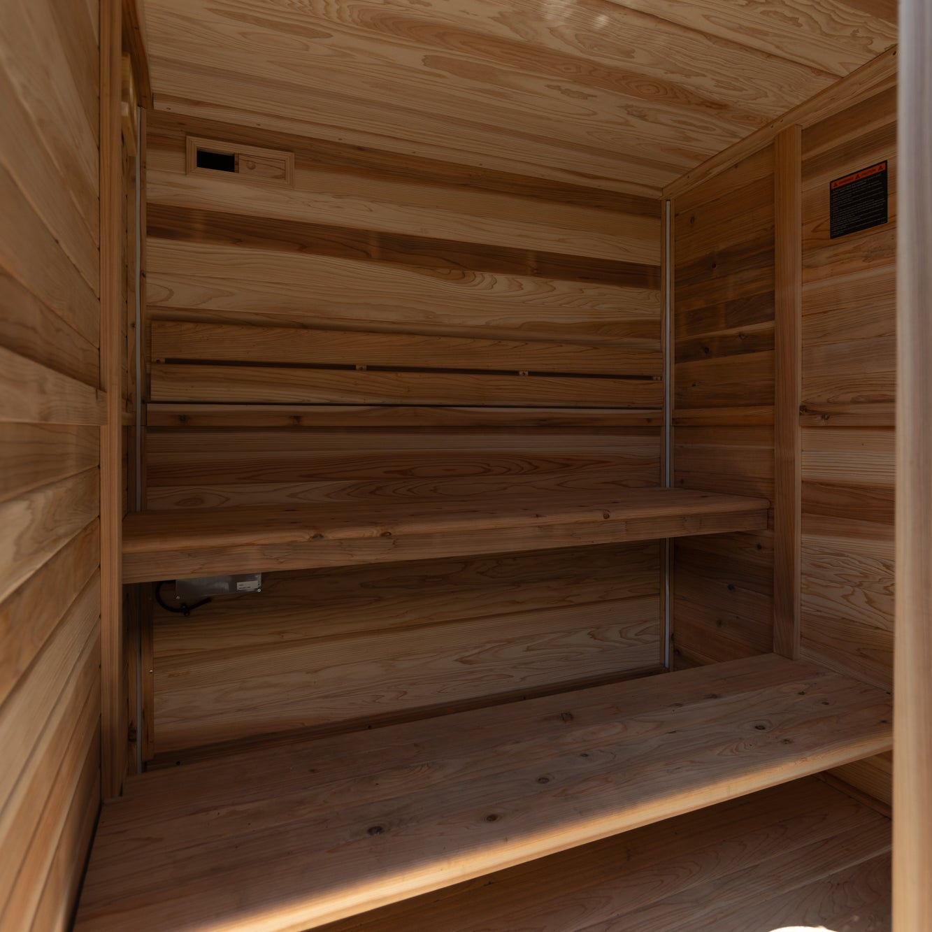 Sereno cedar outdoor sauna with stone heater in a New Zealand backyard setting